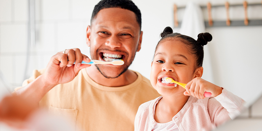 pai e filha fazendo higiene bucal 