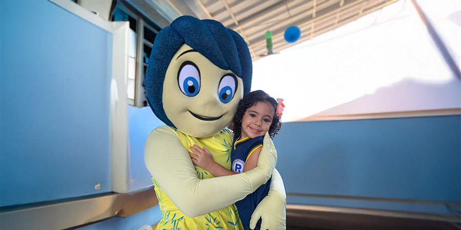 aluna com o mascote da escola - Primeira infância e habilidades cognitivas que sustentam a alfabetização