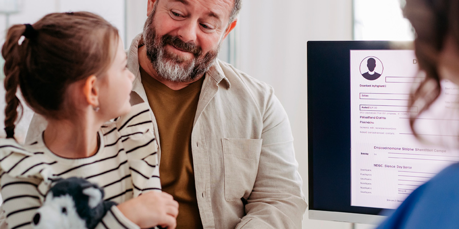 Pai e filha sentados conversando com a professora em frente ao computador