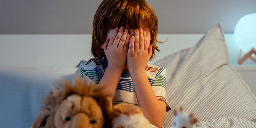 criança com a mão nos olhos e com medo 